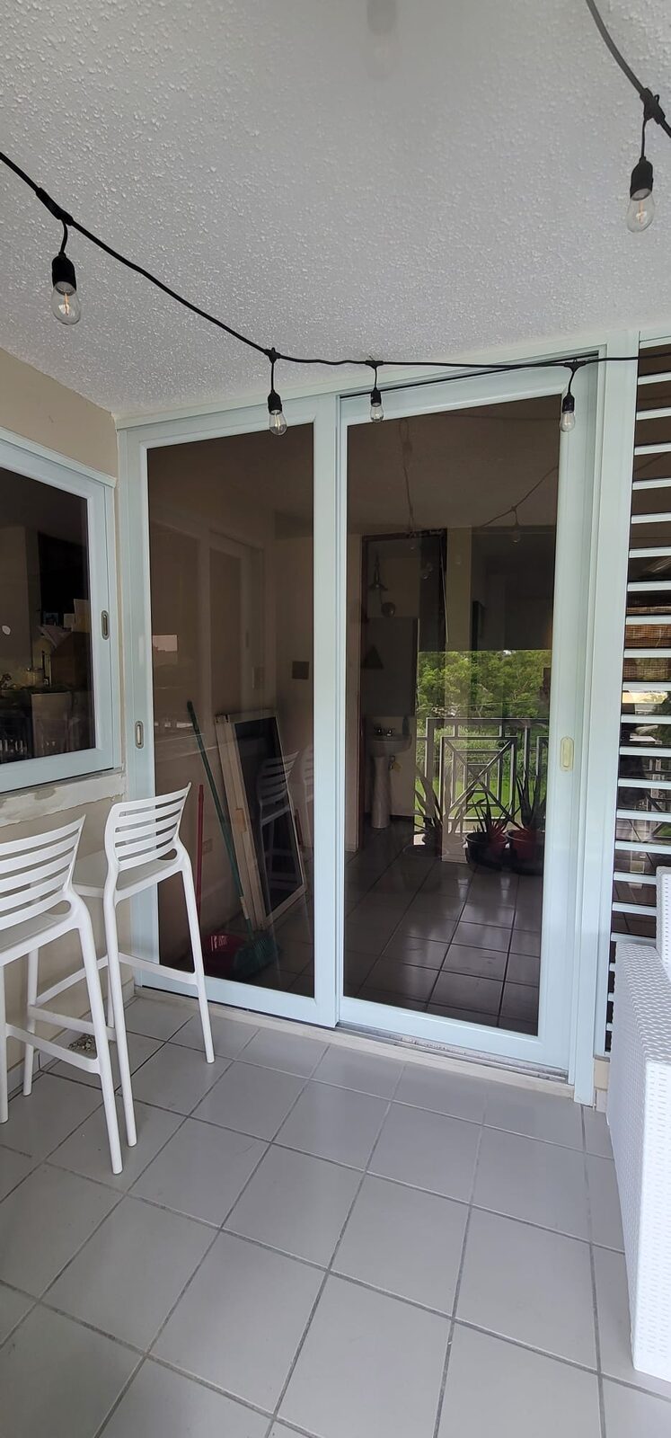 Balcón cerrado con paneles de cristal y aluminio hacia el patio